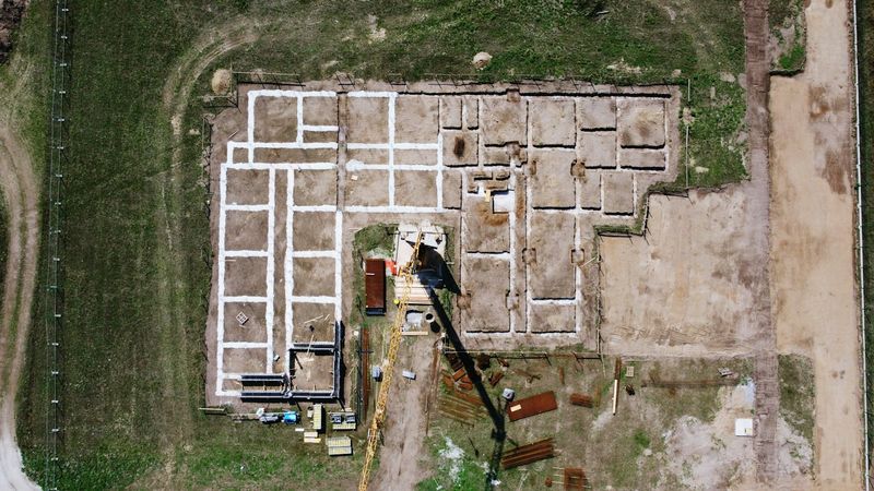 Vista aerea di un cantiere con le fondazioni appena tracciate su un terreno fra i campi