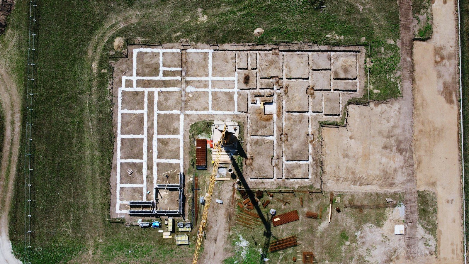 Vista aerea di un cantiere con le fondazioni appena tracciate su un terreno fra i campi