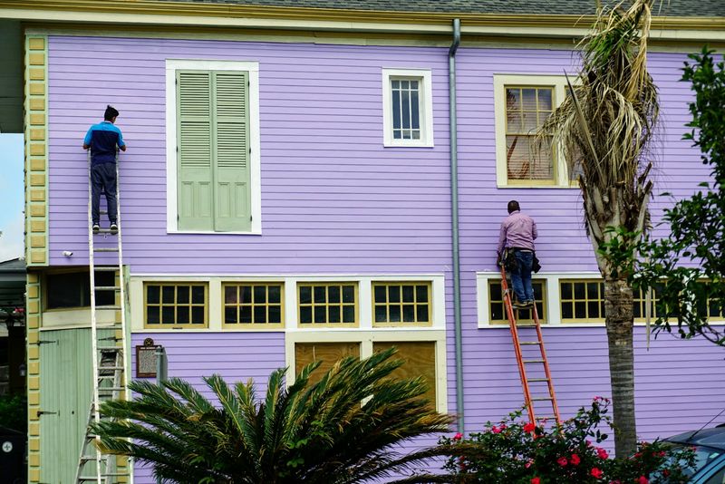 Operai su una scala durante la manutenzione della facciata di una casa