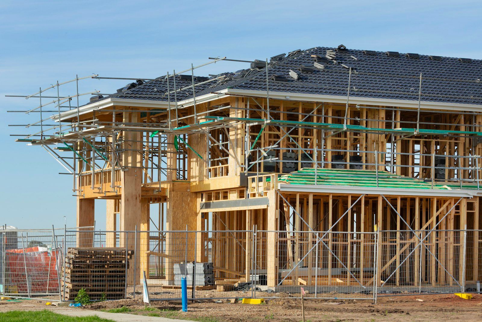 Casa a telaio in legno su due piani in costruzione, con ponteggi e recinzione di cantiere