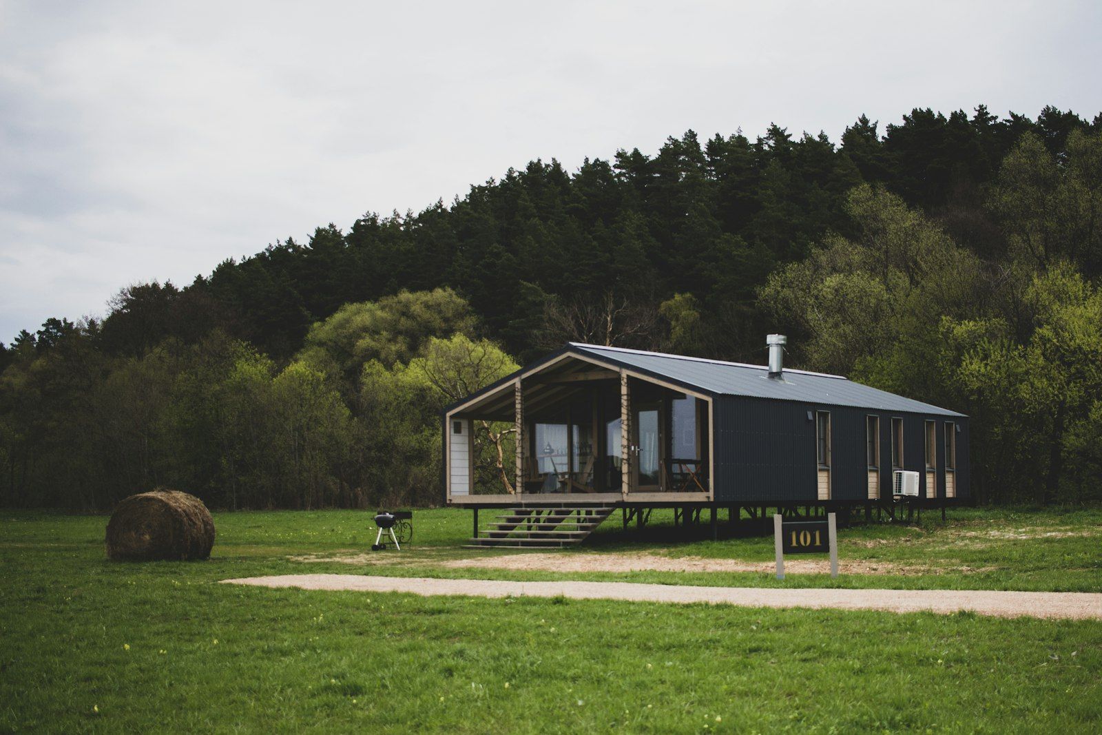 Casa in legno compatta su un solo piano, con portico vetrato, in un prato ai margini del bosco