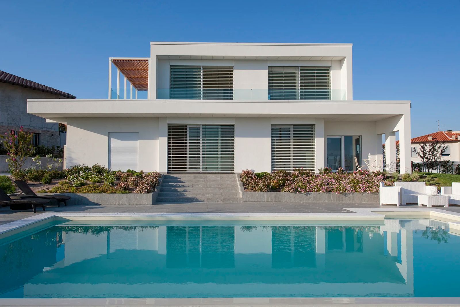Villa contemporanea in legno Subissati su due piani, bianca, con frangisole, terrazza e piscina in primo piano